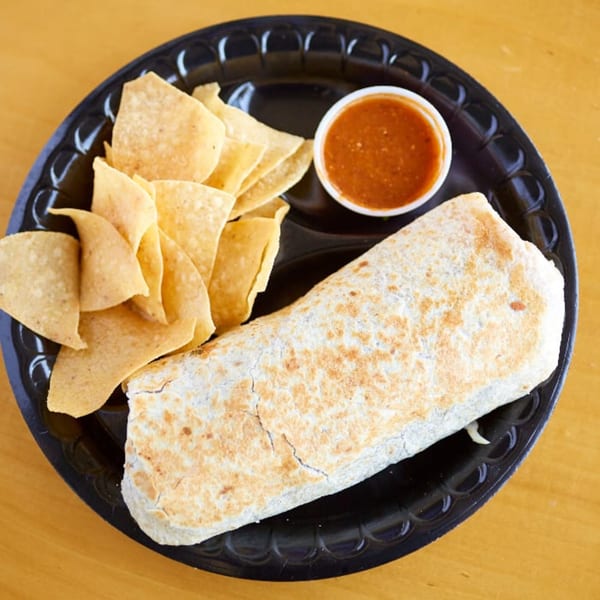 A large burrito, tortilla chips, and a side of salsa on a black plate from Pachanga Mexican Grill.